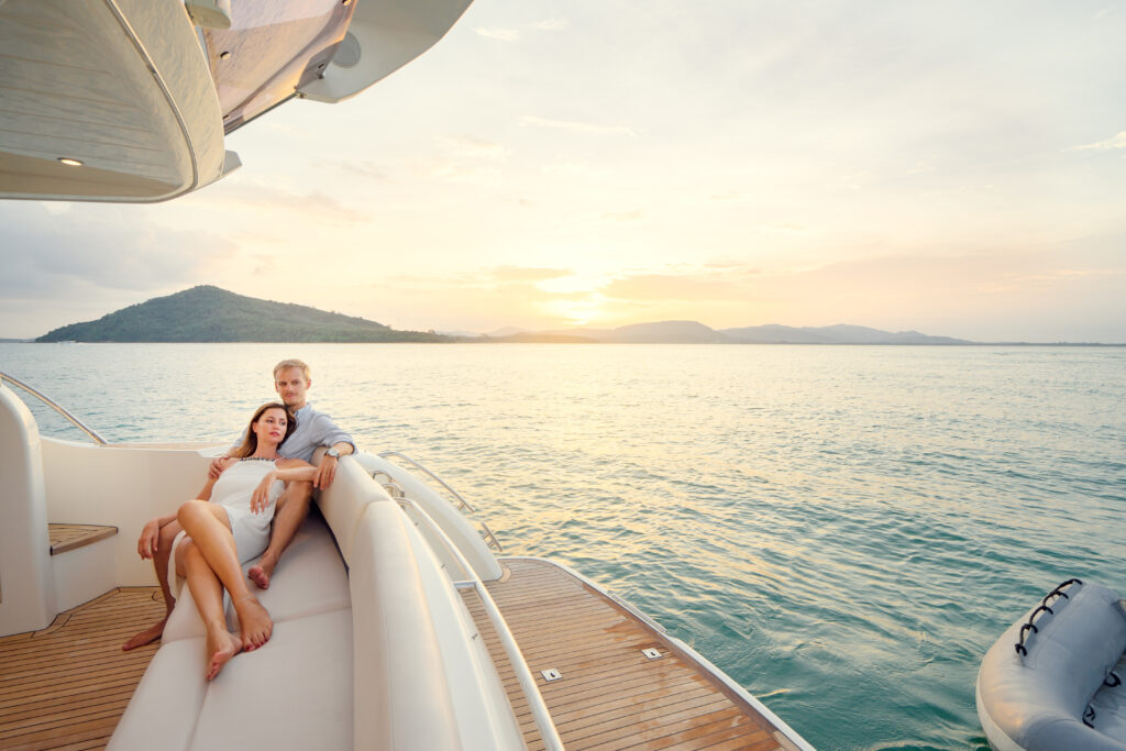 Paar entspannt bei Sonnenuntergang auf dem Achterdeck einer Motoryacht auf dem Meer