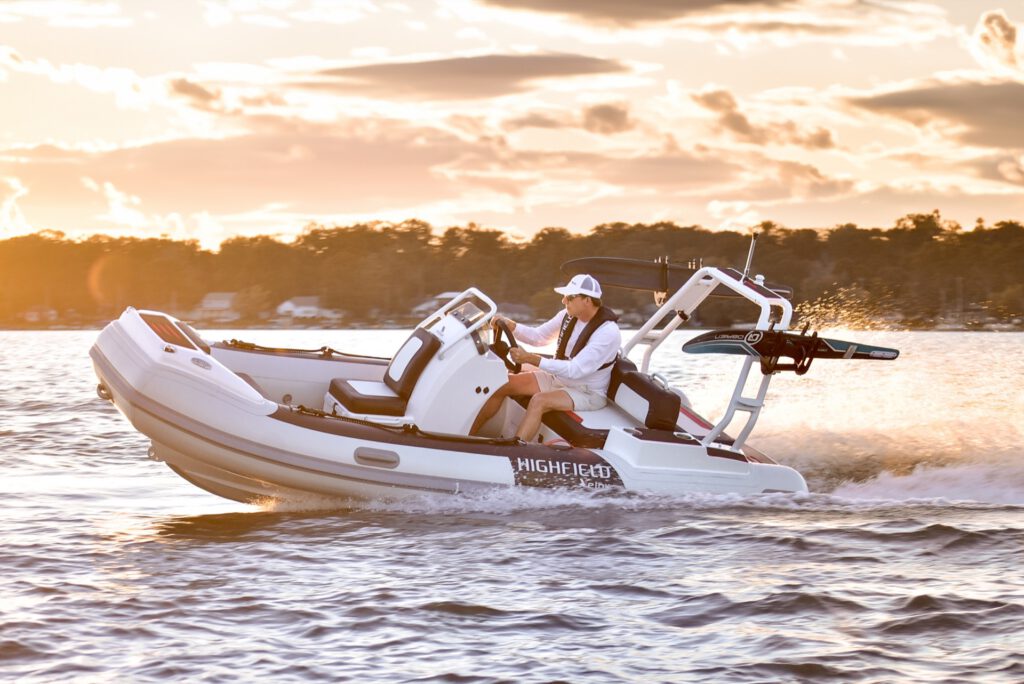 Weisses Schlauchboot mit Fahrer in Fahrt auf dem Wasser bei Sonnenuntergang