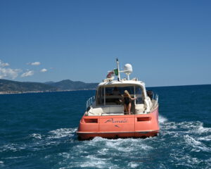 Rote Motoryacht von hinten in Fahrt, Person winkt vom Heck