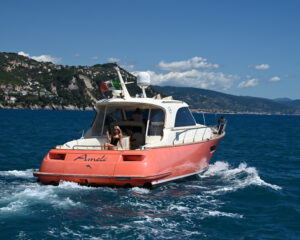Heckansicht einer roten Motoryacht in Fahrt auf blauem Meer