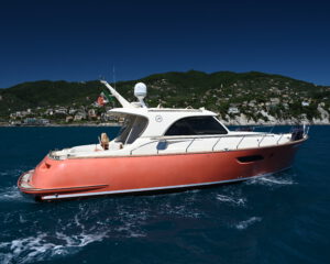 Rote Motoryacht auf blauem Wasser vor huegeliger Kueste