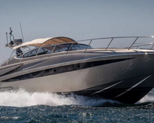 Graue Motoryacht in schneller Fahrt mit Gischt auf offenem Meer