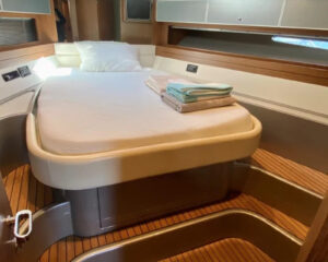 Masterkabine einer Yacht mit Doppelbett, Holzboden und heller Vertaefelung