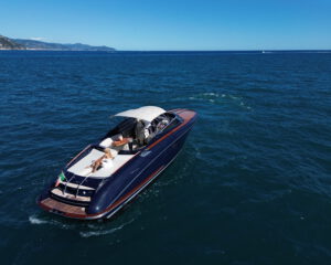 Motoryacht mit dunklem Rumpf und offenem Cockpit auf ruhigem Meer vor Kuestenlinie
