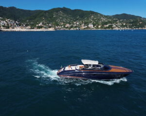 Dunkle Motoryacht mit Holzdeck in Fahrt vor der bergigen Portofino-Kueste