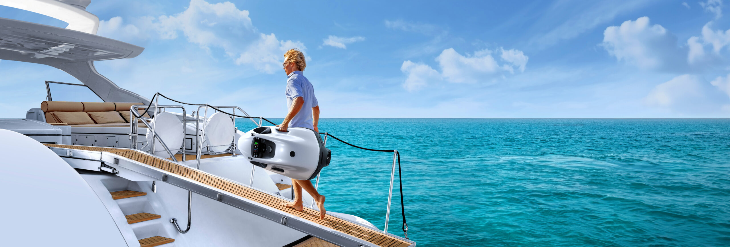 Person hebt einen Seabob am Heck einer Motoryacht über türkisfarbenem Wasser